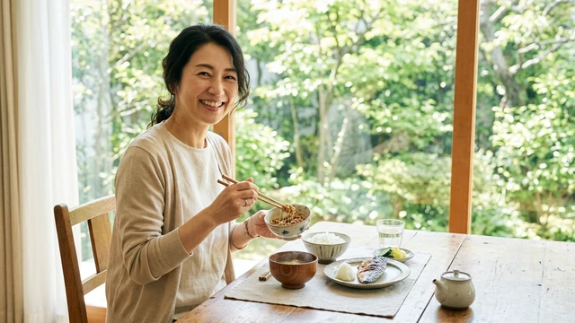 食卓で納豆をかき混ぜる女性